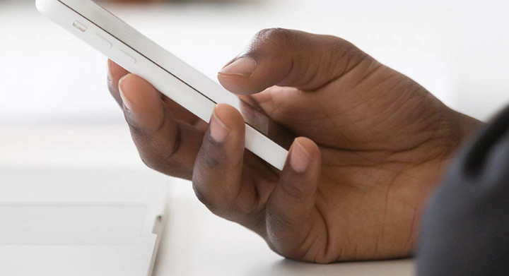 SCHOTT delivers innovation and reliability for the consumer electronics market Hand holding a smartphone next to a laptop on a desk